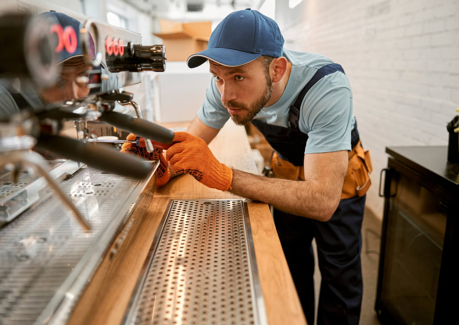 An appliance mechanic working on an espresso machine in a cafe